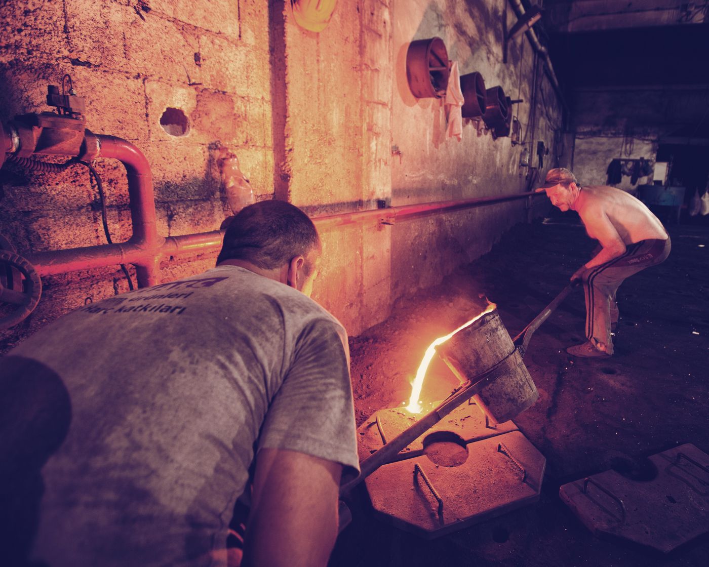 Foundry workers pouring molten gold into moulds during refining